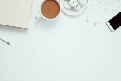 High angle view of coffee cup and dessert with mobile phone on table