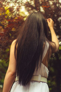 Rear view of woman standing against trees