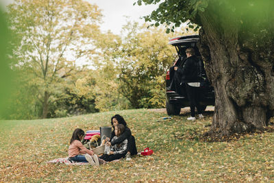 Parents with daughters enjoying picnic during autumn