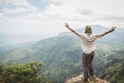 Woman standing on mountain against sky