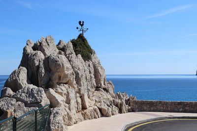 Rock formations by sea against blue sky