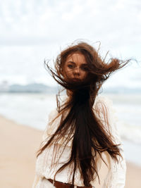 Portrait of young woman standing at beach