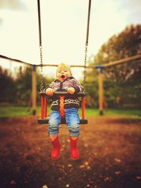 Close-up of boy on swing at playground