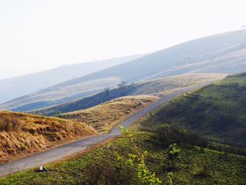 Road leading towards mountains against clear sky