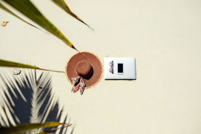 Directly above shot of sunhat with smart phone and sunglasses on beach