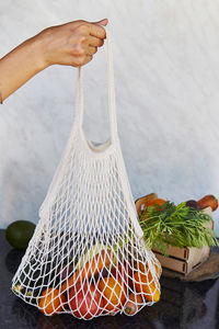 Woman holds eco shopping reusable bag of fresh vegetables - tomatoes, purple potatoes, eggplants
