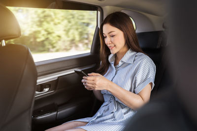 Young woman using mobile phone while sitting in car