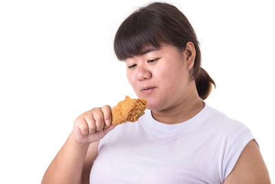 Portrait of woman holding ice cream against white background