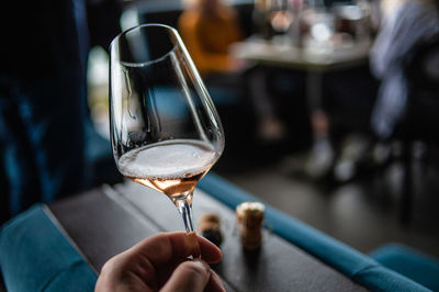 Close-up of hand holding wine glass on table