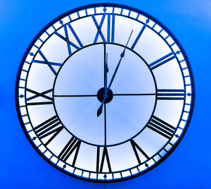 Low angle view of clock against blue sky