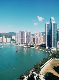 High angle view of city by lake against blue sky