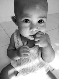 Close-up portrait of cute baby girl sitting on floor at home