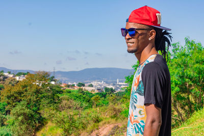 Side view of young man looking away against sky