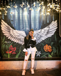 Portrait of young woman standing against graffiti