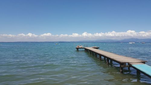 Wooden jetty on lake garda against blue sky