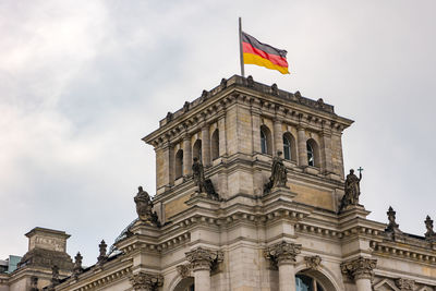 The german flag on the tower of the reichstag building in the government district in berlin, germany