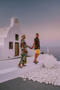 Couple holding hands while standing by church against sky