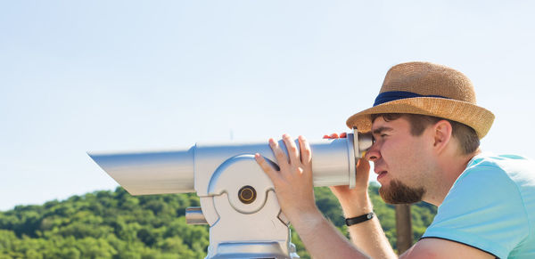 Portrait of young man looking at camera against clear sky