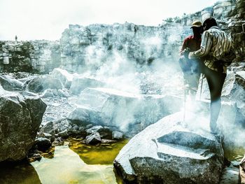 Rear view of people standing on rock