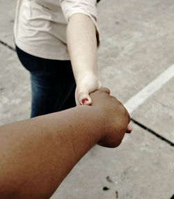 Cropped image of man holding woman hand on street