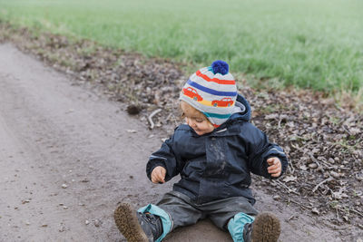 High angle view of boy sitting on dirt road 