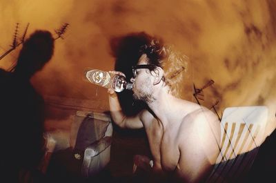 Side view of shirtless man drinking alcohol