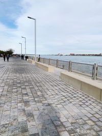 Footpath by sea against sky in city