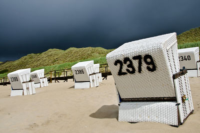 Text on hooded beach chairs against sky