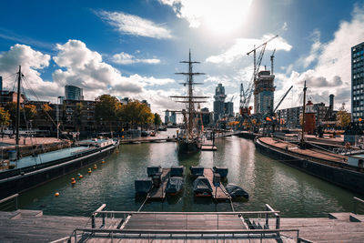 Sailboats on pier by river against sky in city