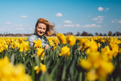 Portrait of smiling young woman with yellow flowers in field