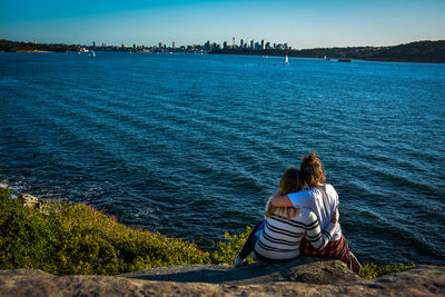 Rear view of women sitting at beach