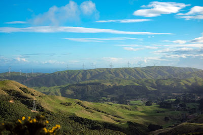 Wind turbines on the green rolling hills of new zealand. scenic view of landscape against sky.