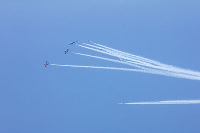 Low angle view of airplanes flying against blue sky