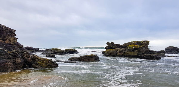 Rock formation on beach against sky