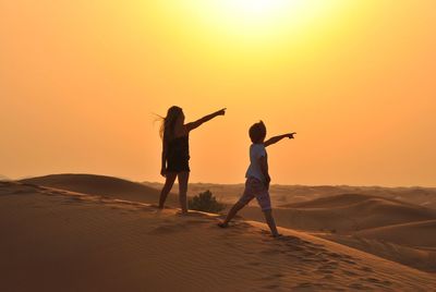 Children on sand dune at sunset