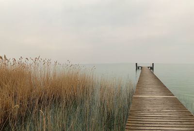 Wooden pier over sea against sky