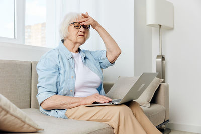 Young woman using mobile phone while sitting at home