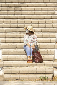 Full length of girl holding basket against brick wall