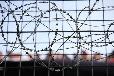 Close-up of barbed wire fence against sky
