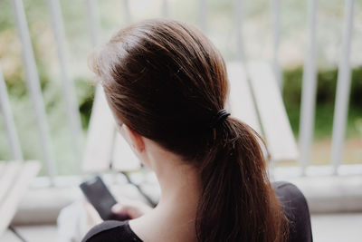 Rear view of woman using phone at home