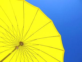 Low angle view of yellow umbrella against clear blue sky