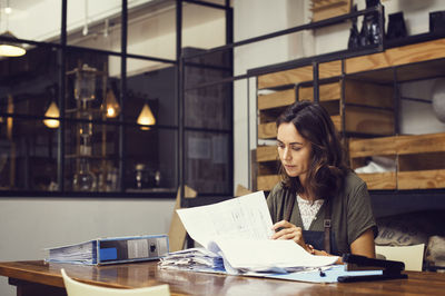 Mature female owner analyzing documents at coffee shop