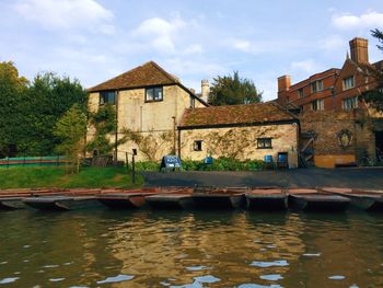 Canal by house and buildings against sky