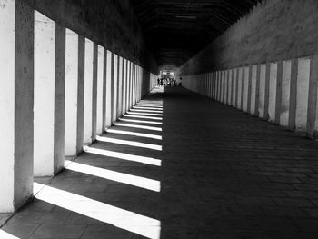 Portico walkway in a buddhist temple in myanmar, sunlight shining through the rectangular pillars.