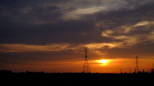 Silhouette electricity pylon on field against sky during sunset