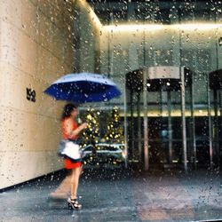 Woman seen through wet window in rainy season