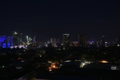 Illuminated buildings in city against clear sky at night