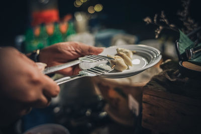 Cropped hands serving food in plate