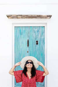 Portrait of young woman standing against wall