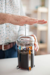 Midsection of man making coffee at home